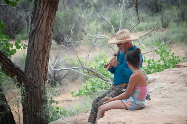 Grand Canyon Youth river guide playing flute with a child