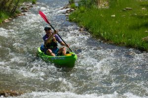 Grand Canyon Youth Field staff director Jean-Philippe rowing a green hard shell kayak