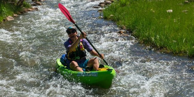 Grand Canyon Youth Field staff director Jean-Philippe rowing a green hard shell kayak
