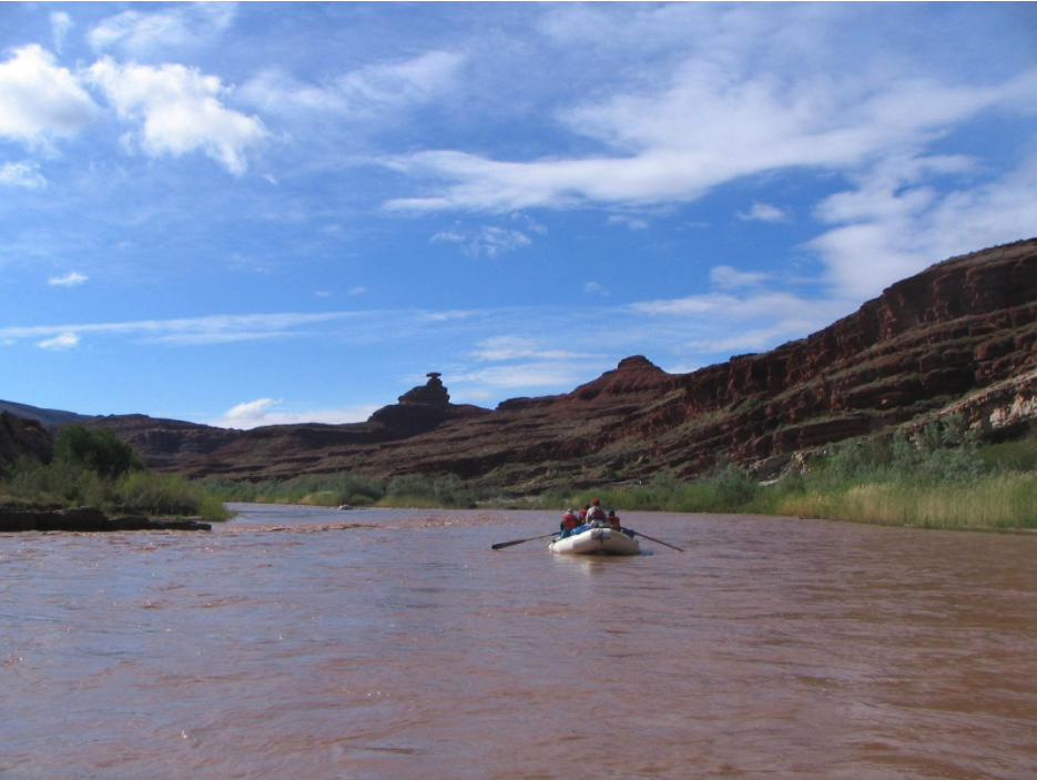 a white boat floats on the san juan river by mexican hat